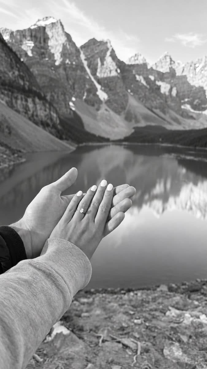 Les mains de Marielle et Michaël et la bague de fiançailles devant un lac de montagne